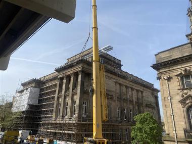 A large yellow crane next to The Harris building