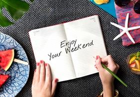 A persons hands with a book saying Happy Weekend.