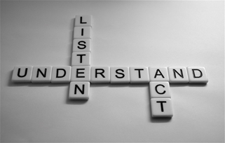 Scrabble pieces on a white background spelling out Listen, Understand and Act.