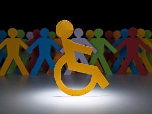 Paper cut outs of a person in a wheelchair with other people in the background.